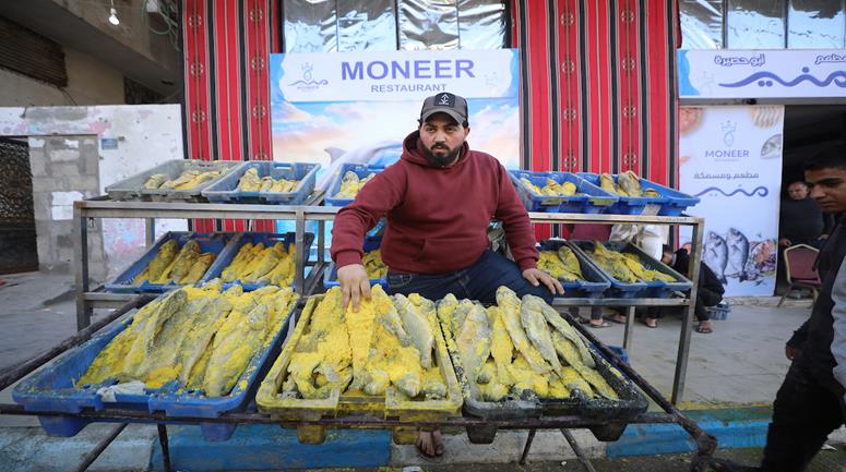 منير أبو حصيرة يجهز السمك المملح لبيعه في مخيم الشاطئ غرب مدينة غزة مع اقتراب عيد الفطر