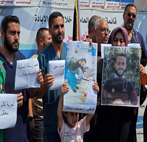 أطباء وعاملون في القطاع الصحي، يشاركون في وقفة بمجمع ناصر الطبي في خان يونس، للمطالبة بالإفراج عن الكوادر الطبية المحتجزة في السجون الإسرائيلية