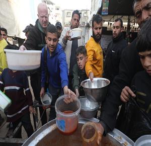 نازحون يتجمعون لتلقي وجبات طعام من مطبخ خيري قبيل موعد الإفطار في مخيم النصيرات، وسط قطاع غزة