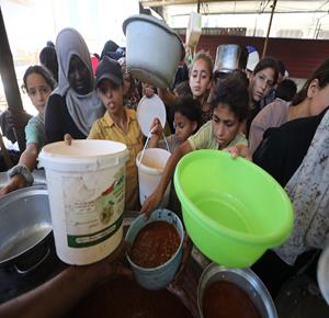 نازحون يتجمعون للحصول على وجبات الطعام من تكية خيرية في مخيم النصيرات وسط قطاع غزة