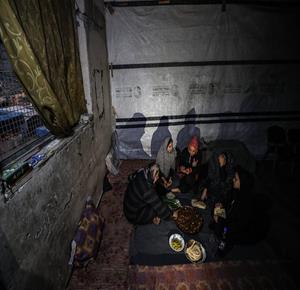 النازحة أم صقر حمد خلال إفطارها مع أطفالها في مكان نزوحها داخل أحد مراكز الإيواء التابعة للأونروا في مدينة غزة، في ظل أوضاع إنسانية صعبة يعيشها النازحون مع حلول شهر رمضان