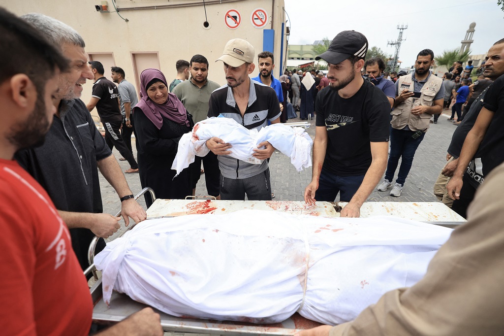 رجل يحمل جثمان طفل ارتقى خلال عدوان الاحتلال على قطاع غزة (تصوير: أ ف ب)